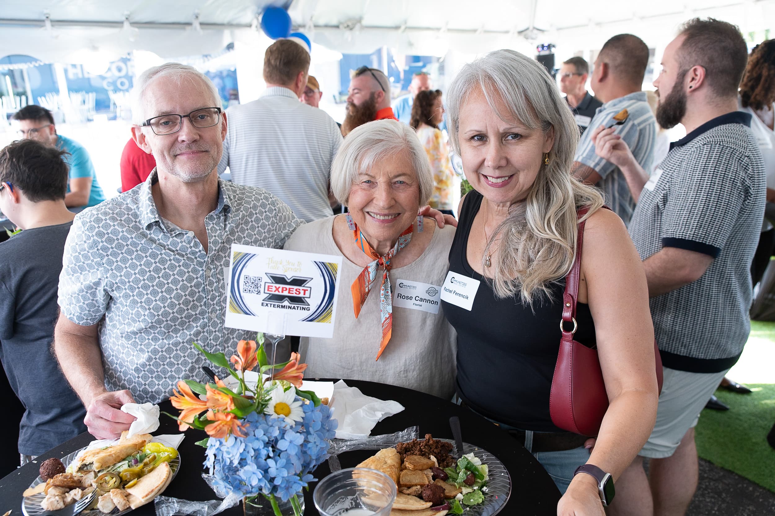 Guests smiling under the tent at Communities Real Estate grand opening celebration