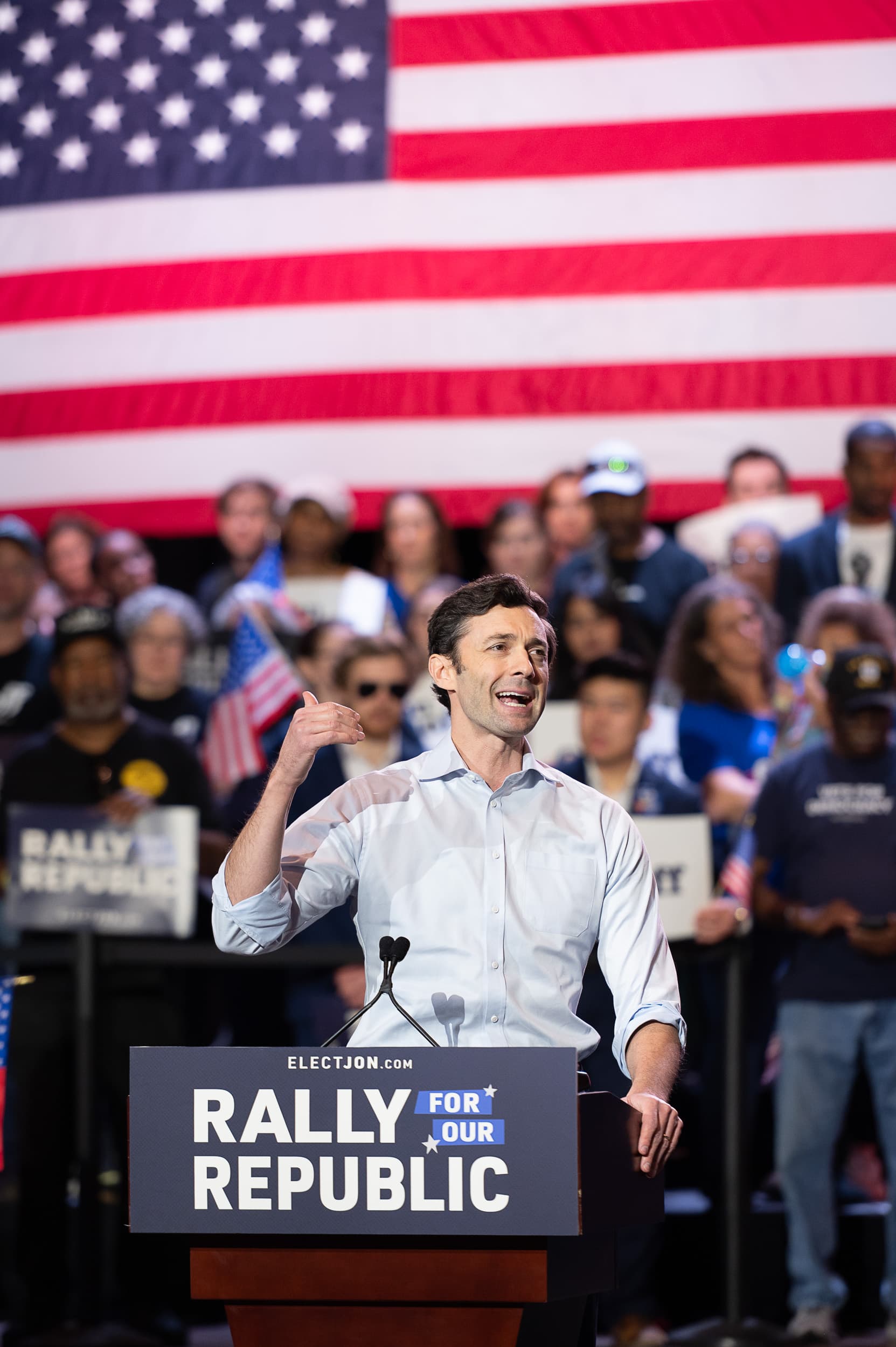 Speaker at podium with American flag backdrop at large-scale Atlanta political event