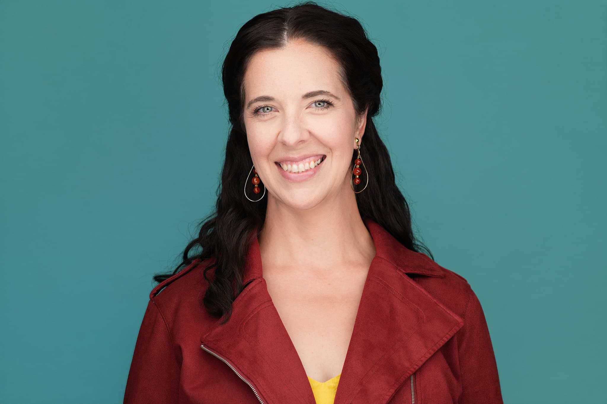 Actor headshot of woman in burgundy jacket against teal backdrop in Decatur studio