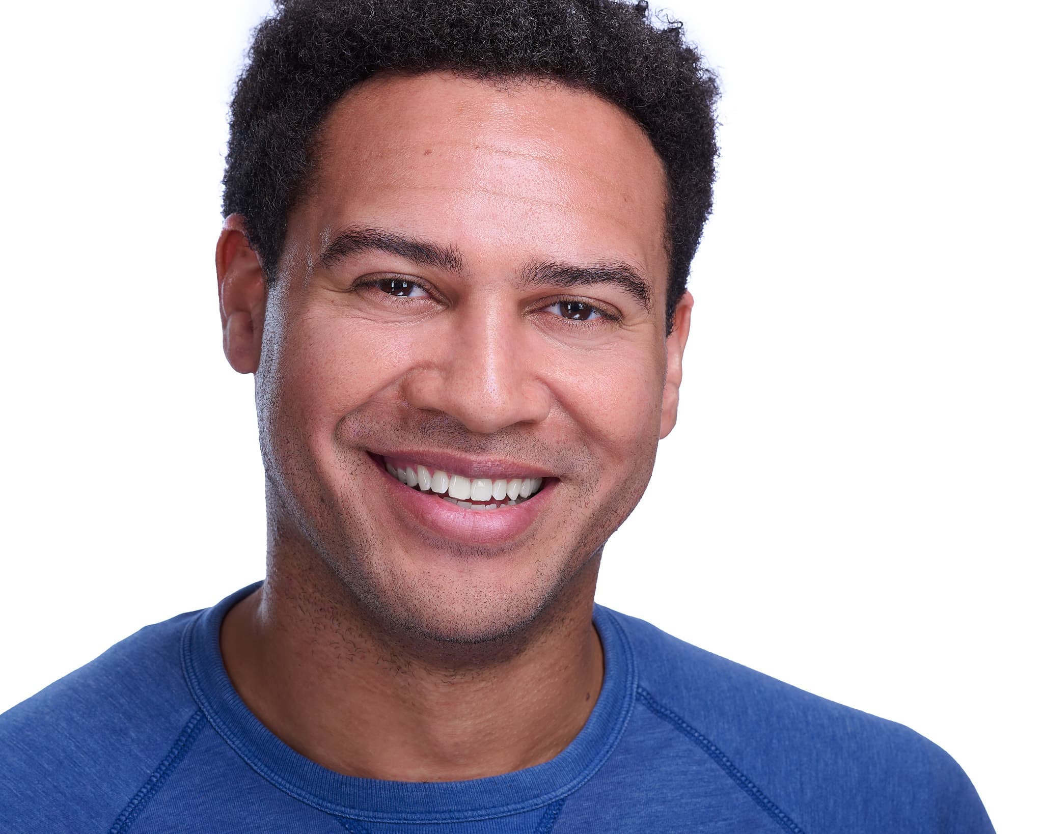 Commercial actor headshot of smiling man in blue crew neck against white backdrop