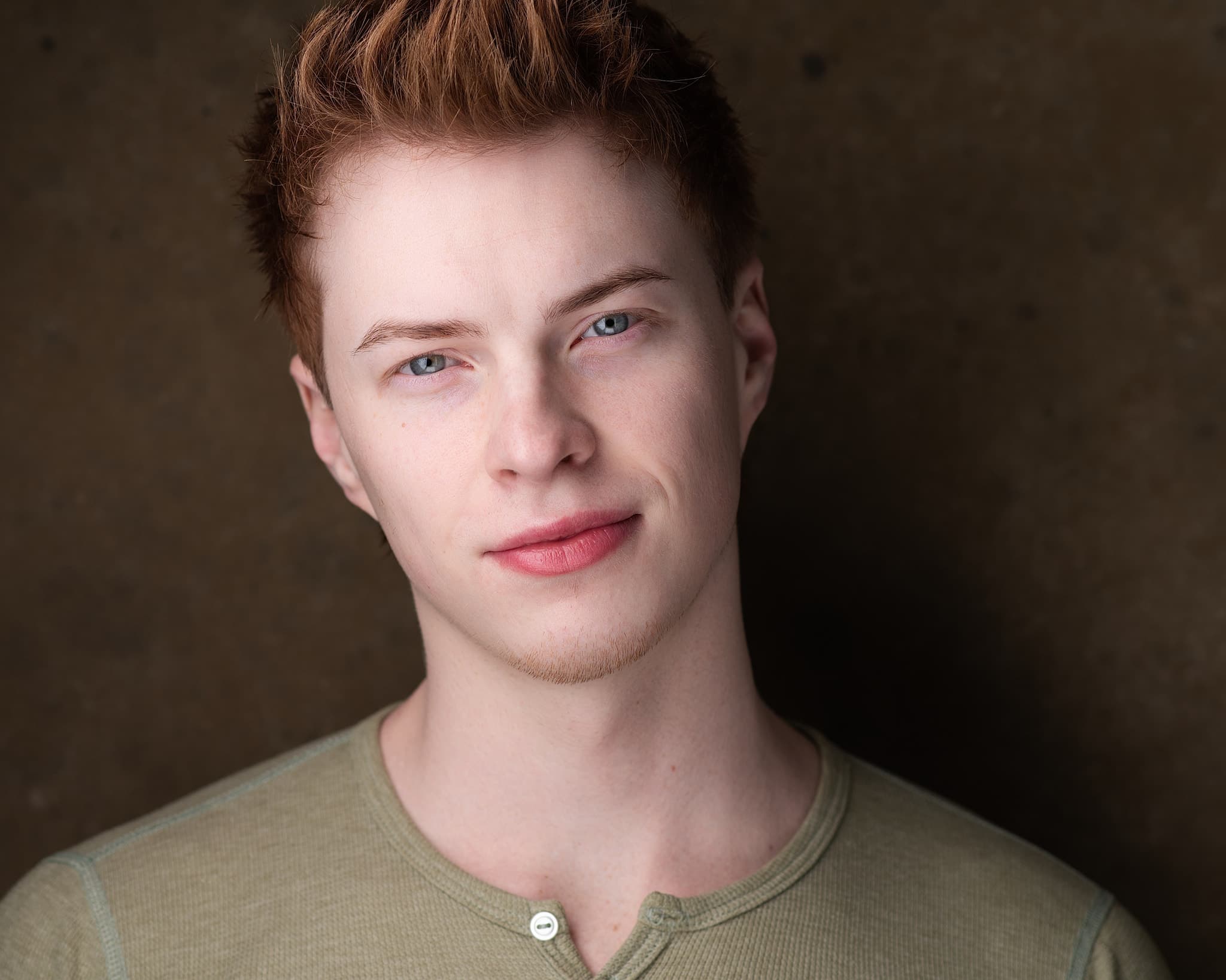 Atlanta actor headshot of Colton Sims, young male performer in sage green henley with confident expression and warm studio lighting