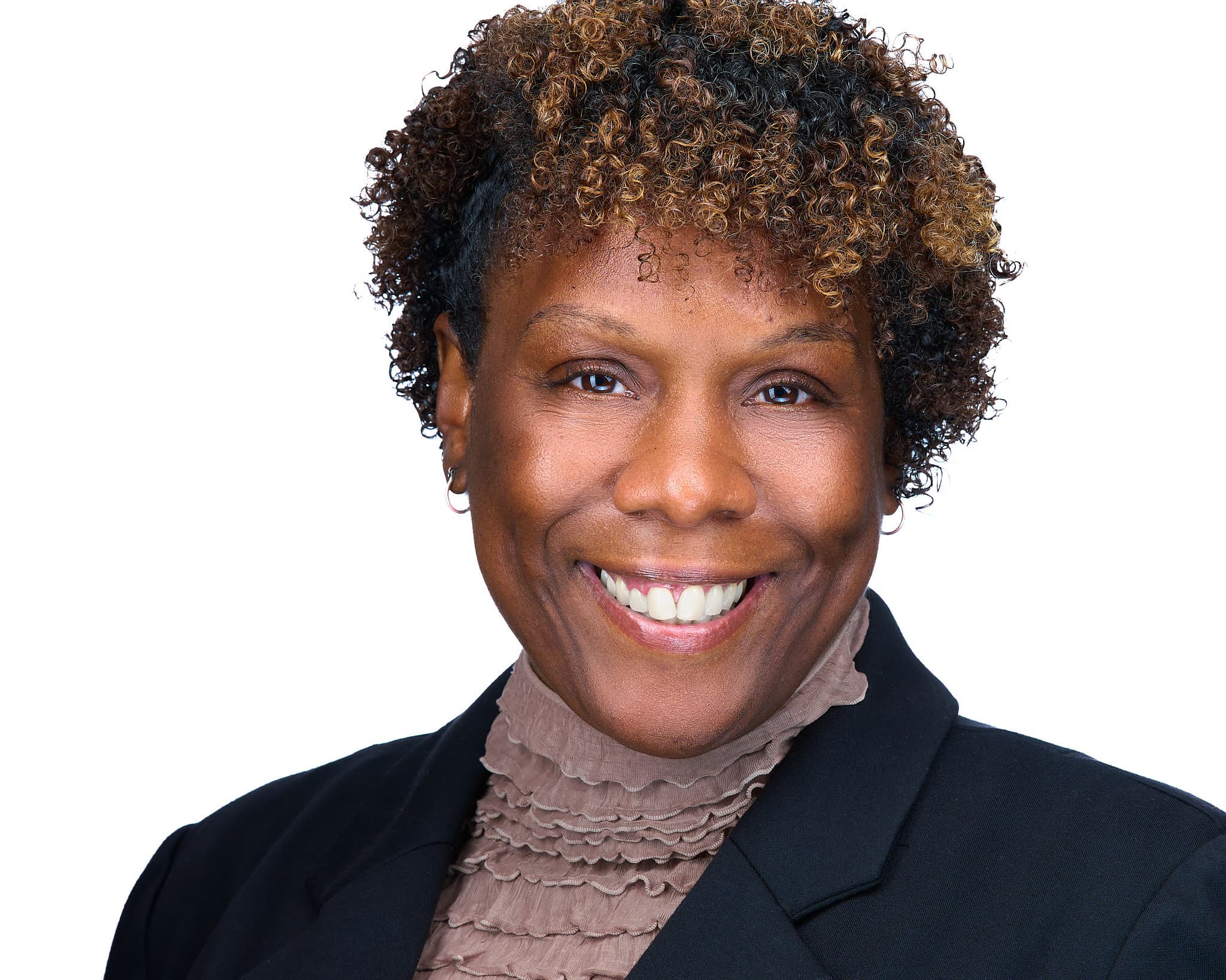 Female executive headshot with warm smile, navy blazer and taupe turtleneck against white background