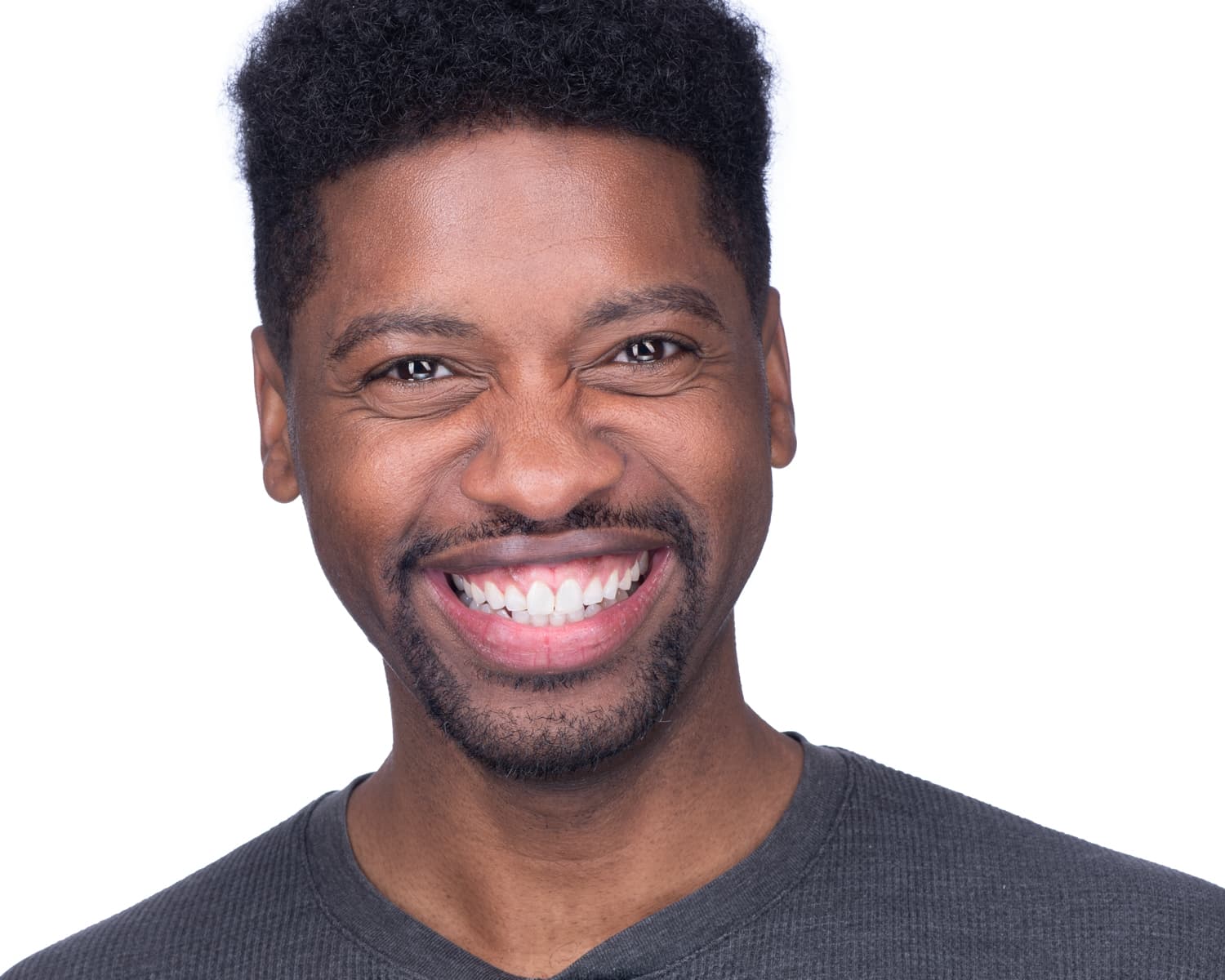 Atlanta commercial actor headshot of Darius Davis, broad smile and warm expression in gray v-neck against bright white studio background