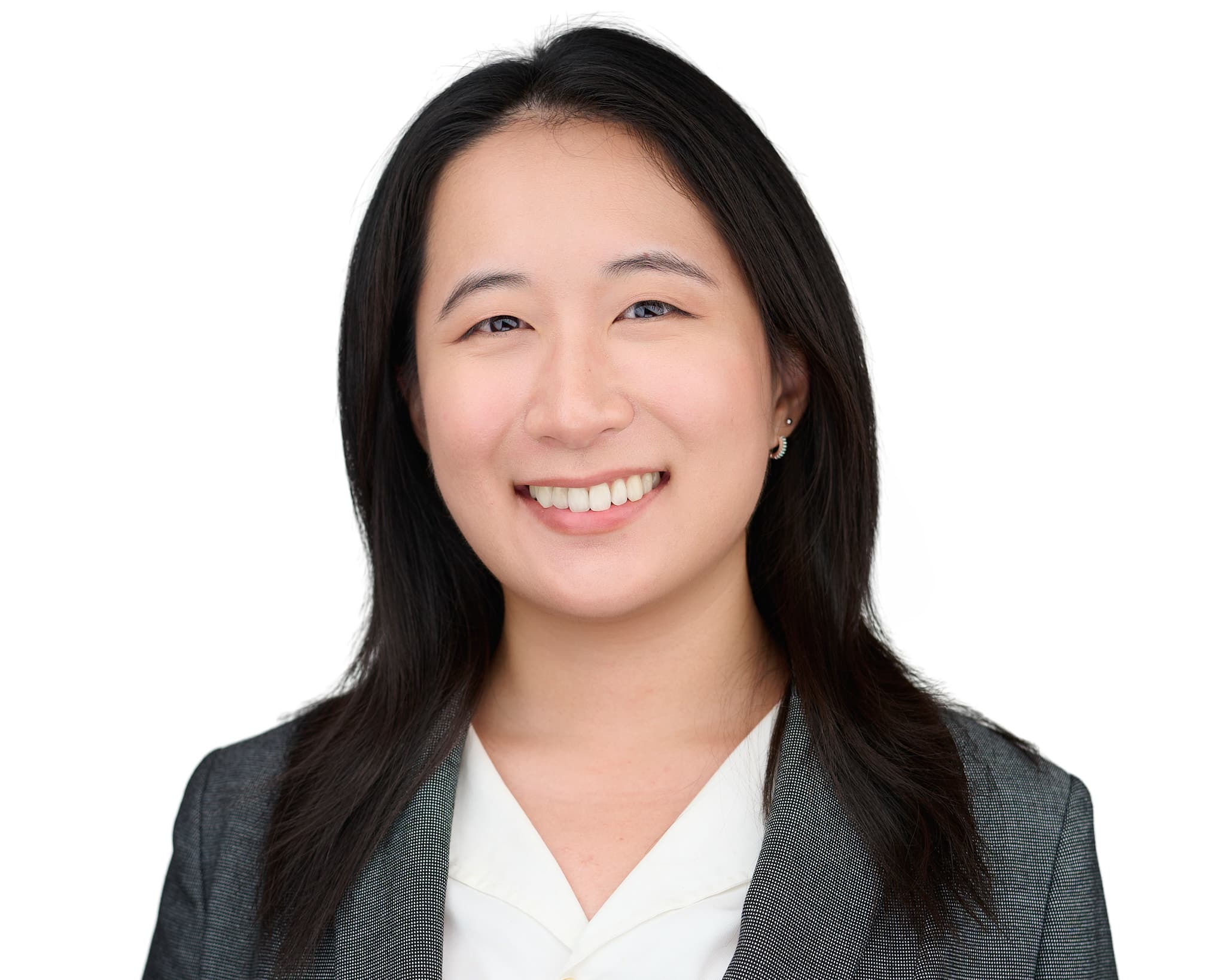 Young professional woman's headshot in gray suit with friendly smile against bright white background