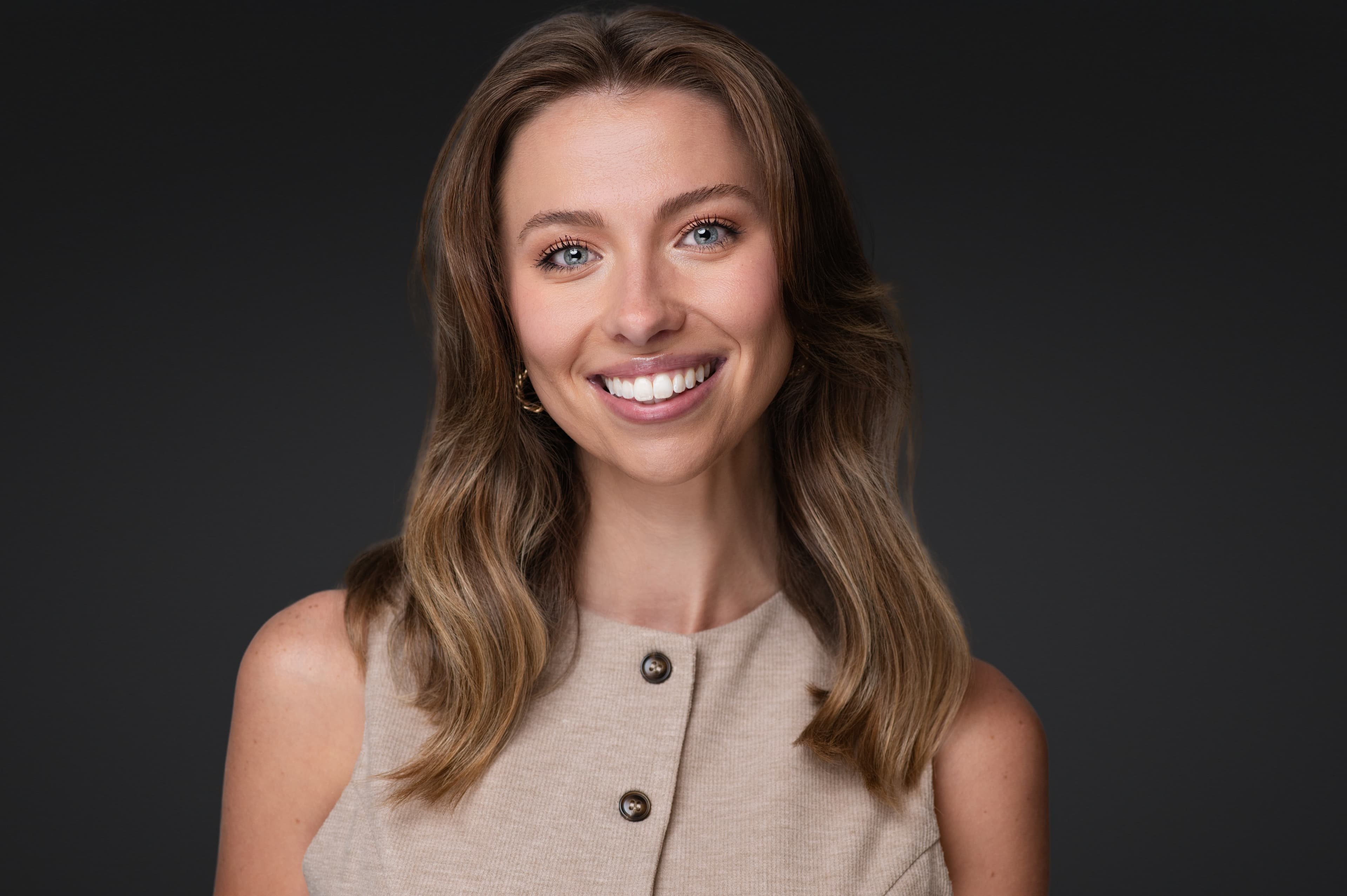 Professional corporate headshot of woman in cream ribbed knit top with warm smile and direct eye contact